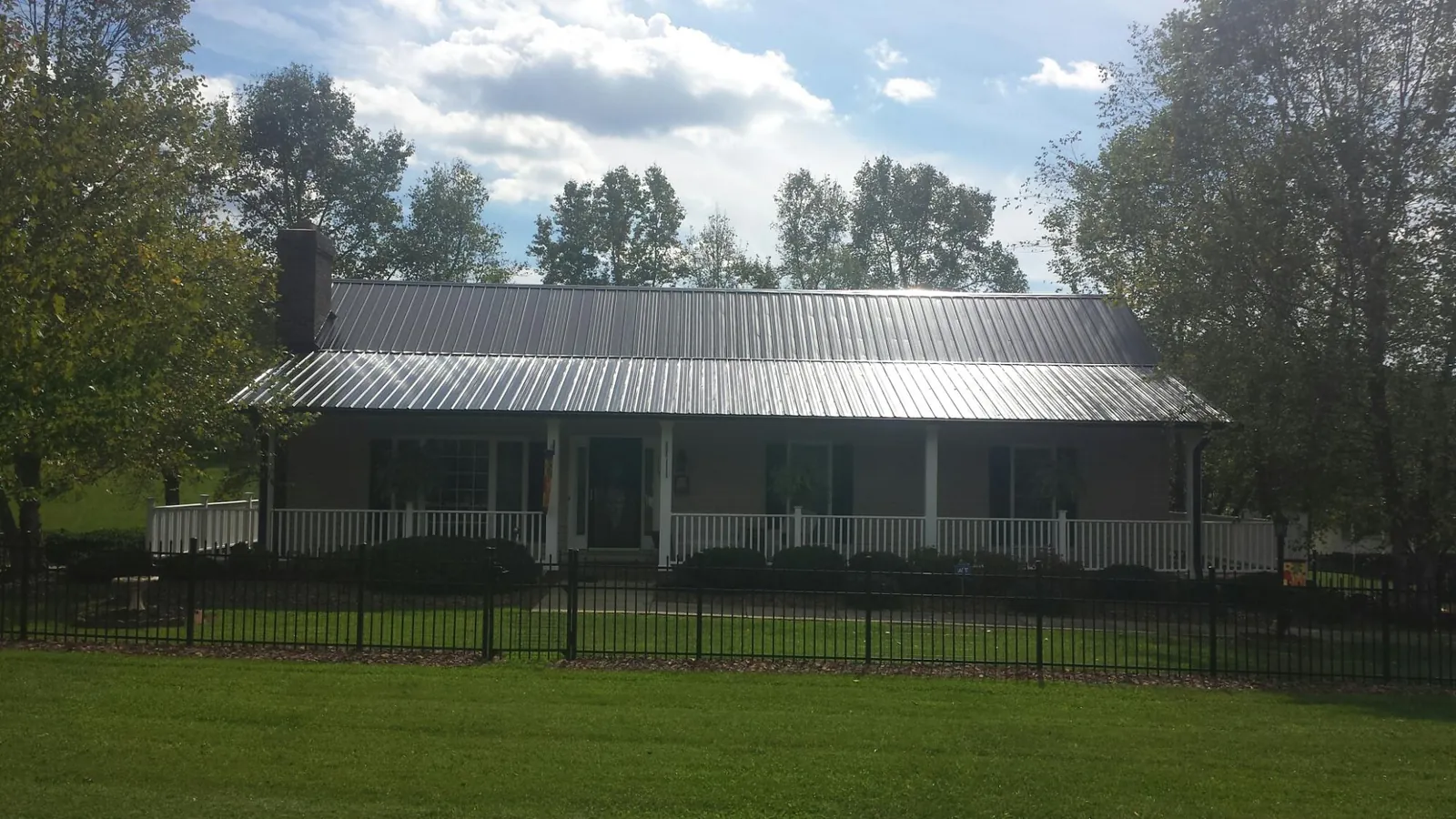Gray metal roof on a brick ranch with a full width front porch — Gutter Guard Installation work by our crew in Lincolnton