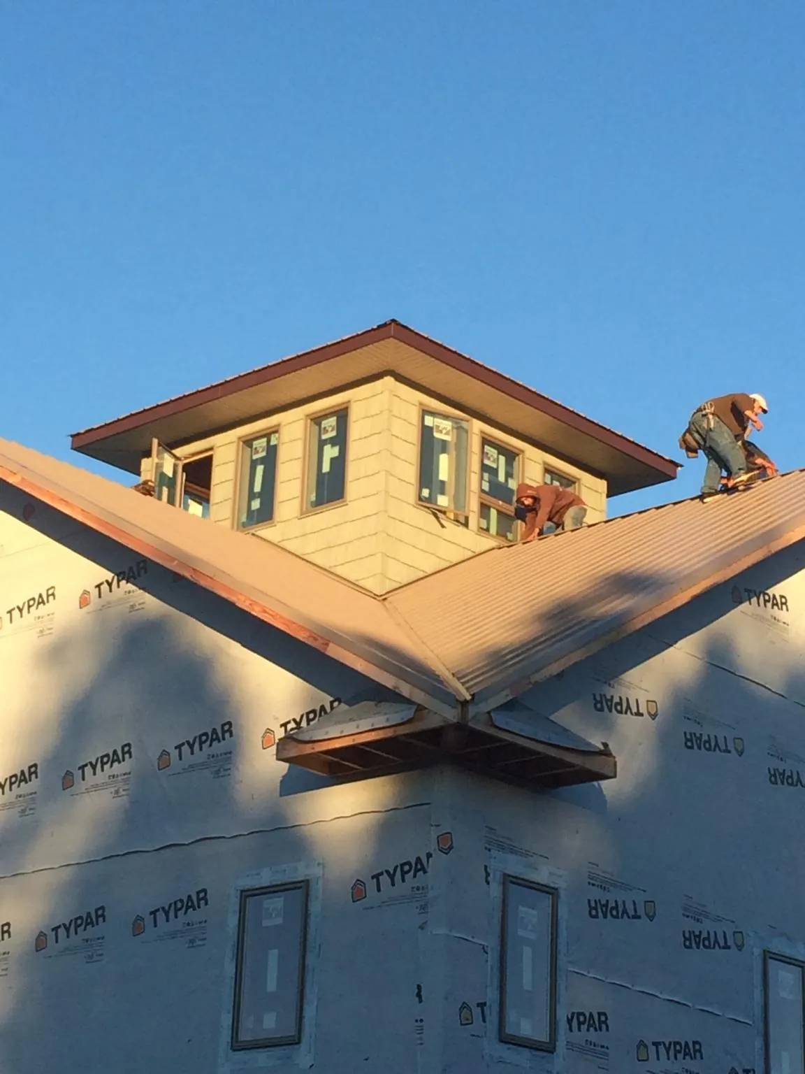 Roofers working around a rooftop cupola on a new metal roof at sunset — Roof Waterproofing in Lincolnton by Roofing Brothers